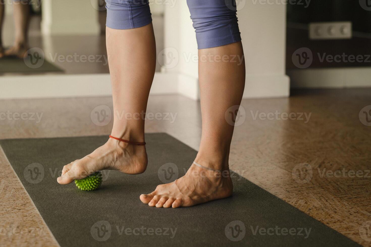 Close - up of the legs of a woman performing gymnastic exercises to correct flat feet during ball massage at home photo