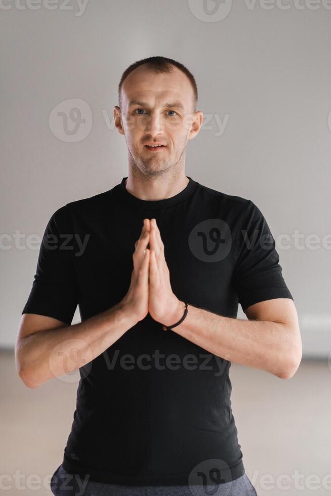 An athletically built man does yoga in the gym on a mat photo