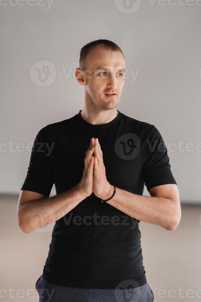 An athletically built man does yoga in the gym on a mat photo