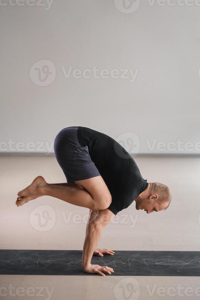 An athletically built man does yoga in the gym on a mat photo