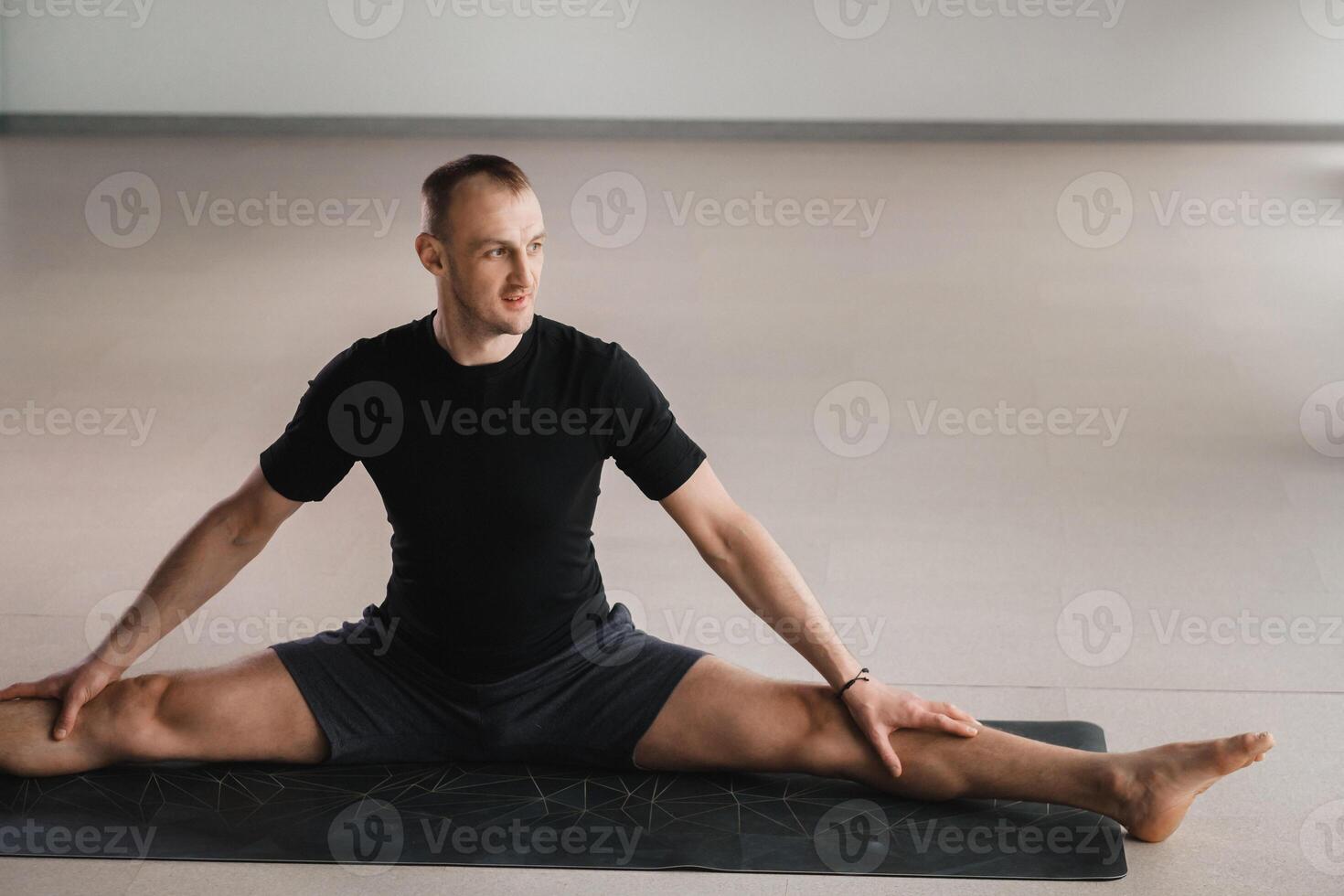 An athletically built man does yoga in the gym on a mat photo