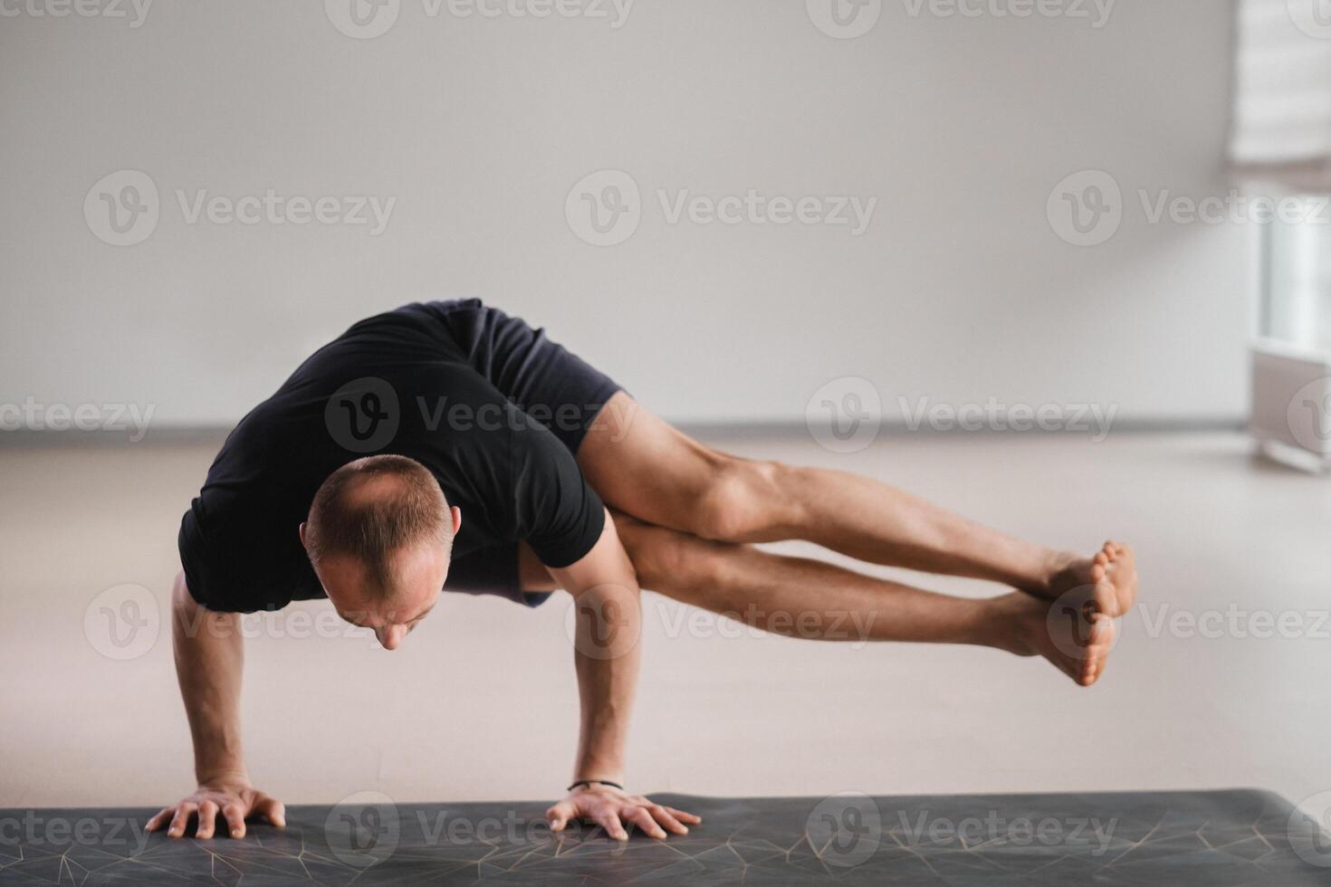 An athletically built man does yoga in the gym on a mat photo
