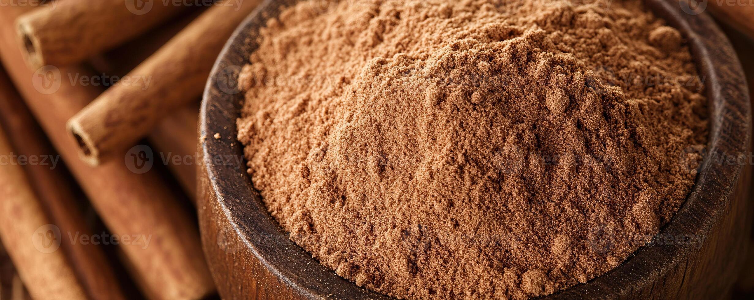 Ground cinnamon powder in a wooden bowl with cinnamon sticks, ideal for culinary and baking themes. photo