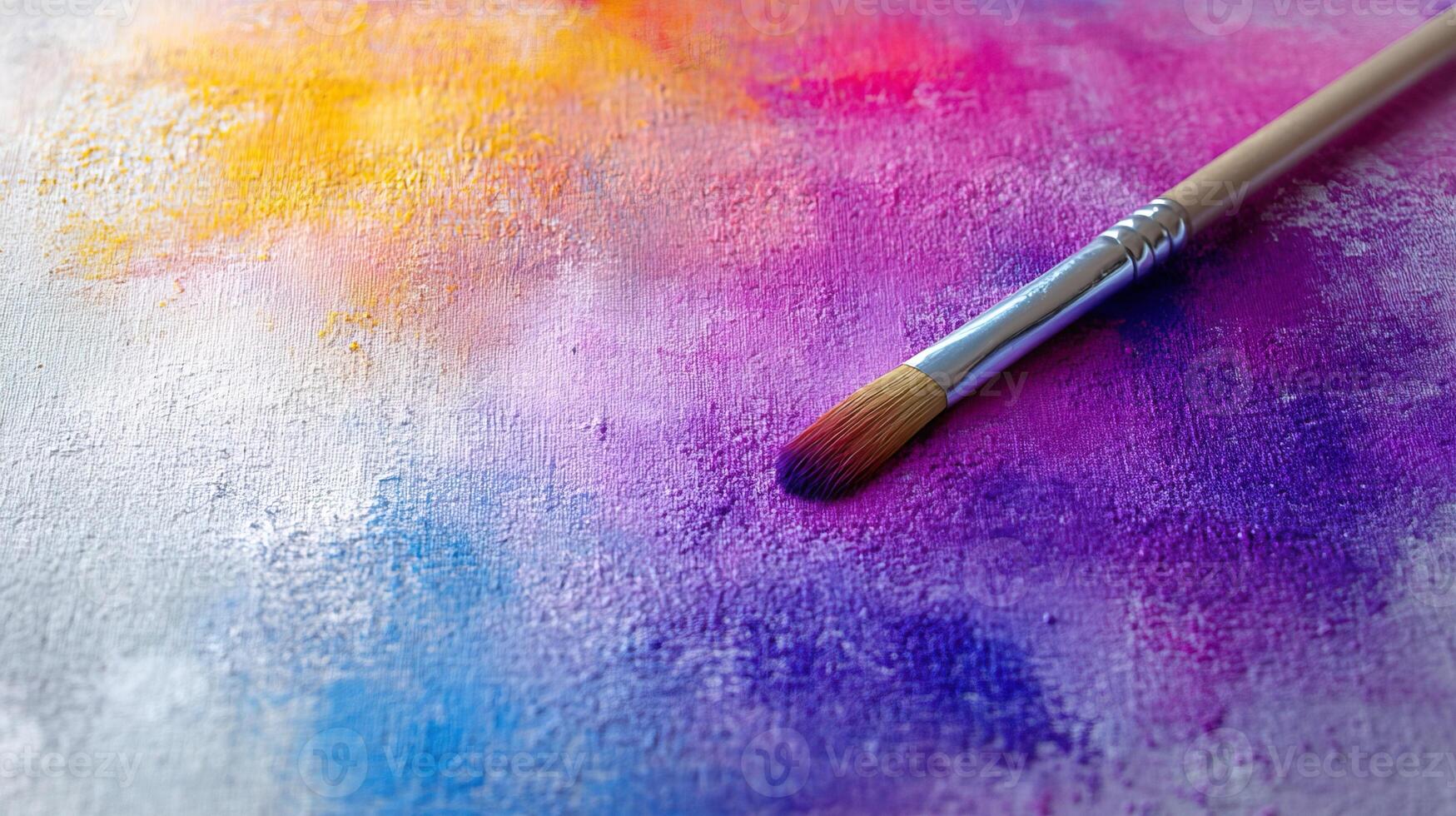 Paintbrush on colorful canvas, showcasing vibrant hues of purple, pink, orange, and blue against a textured background. photo