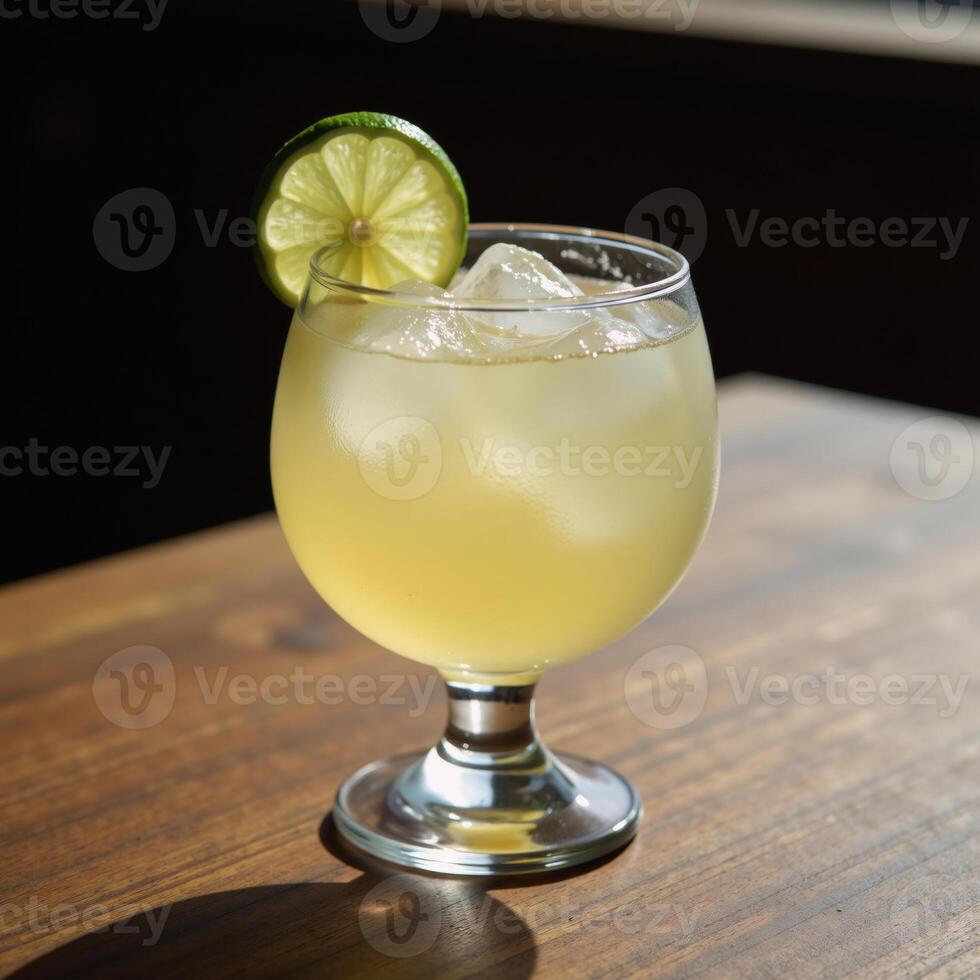 Clear glass filled with a refreshing margarita drink and garnished with lime slice serves invitingly on a rustic wood table photo