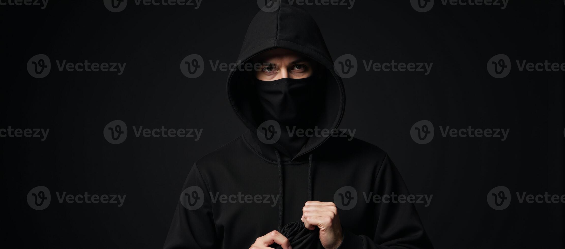 A shadowy bank robber stands against a dark backdrop clutching a bag of stolen cash outlined by a hint of a closed bank door photo