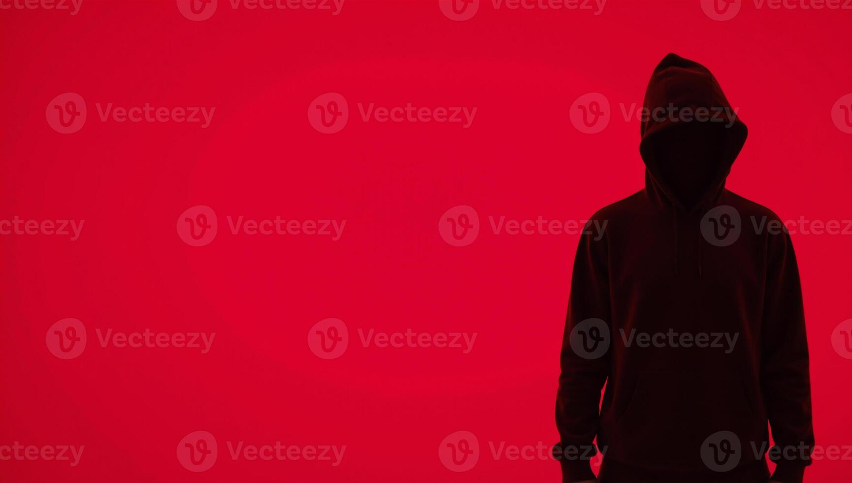 Man in hood with no visible face silhouetted against red background photo