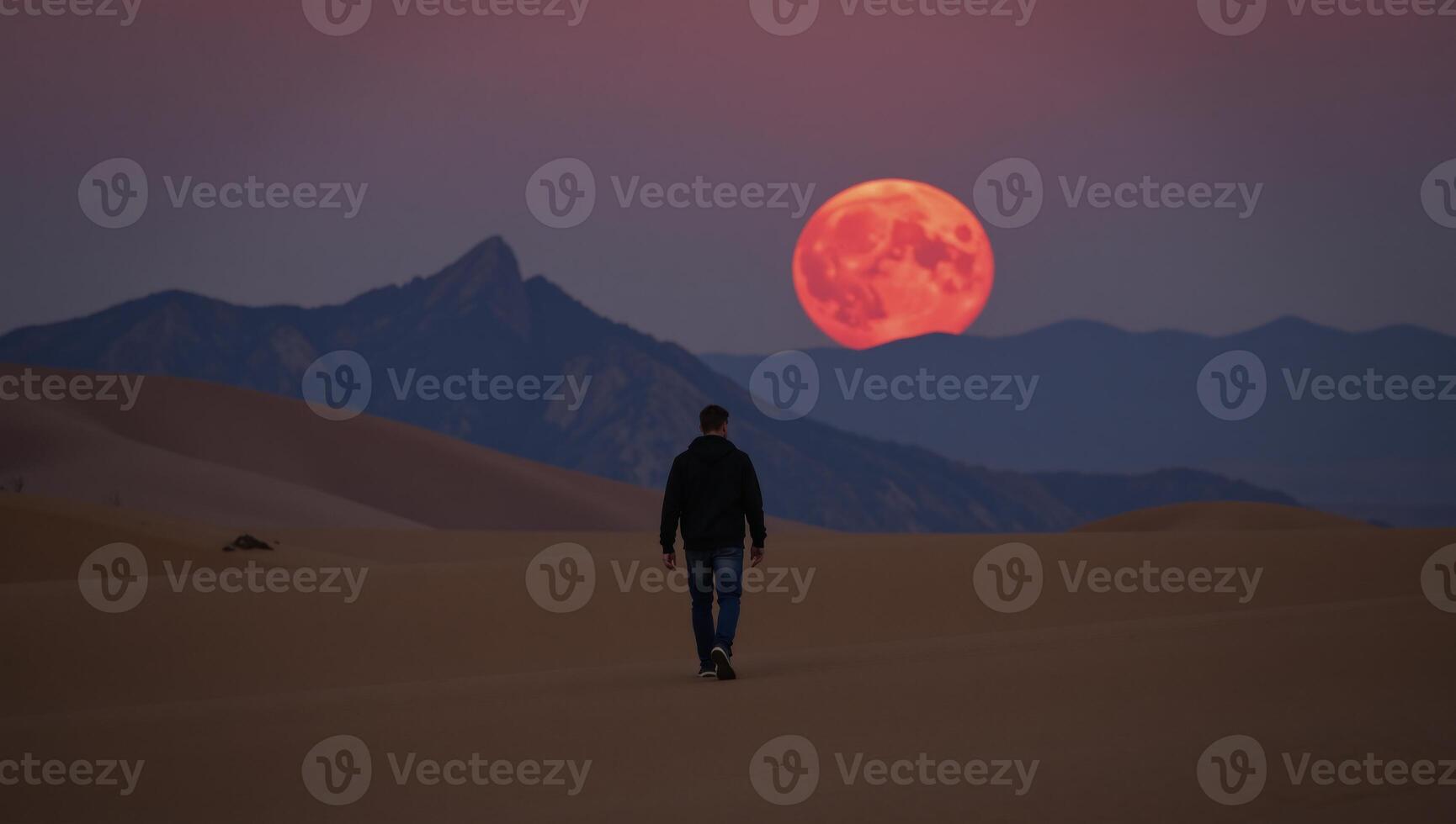 A solitary character traverses a barren desert under a bloodred moon photo