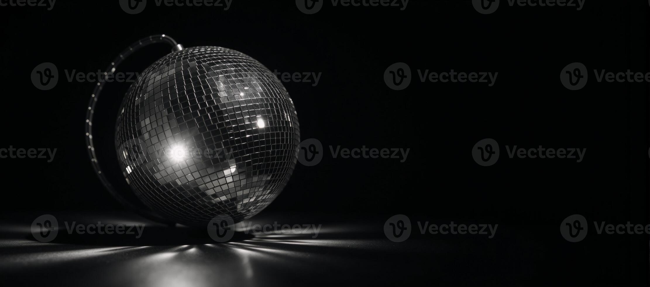A rotating blackandwhite disco ball glows against dark background amidst flashes of light and dramatic shadows photo