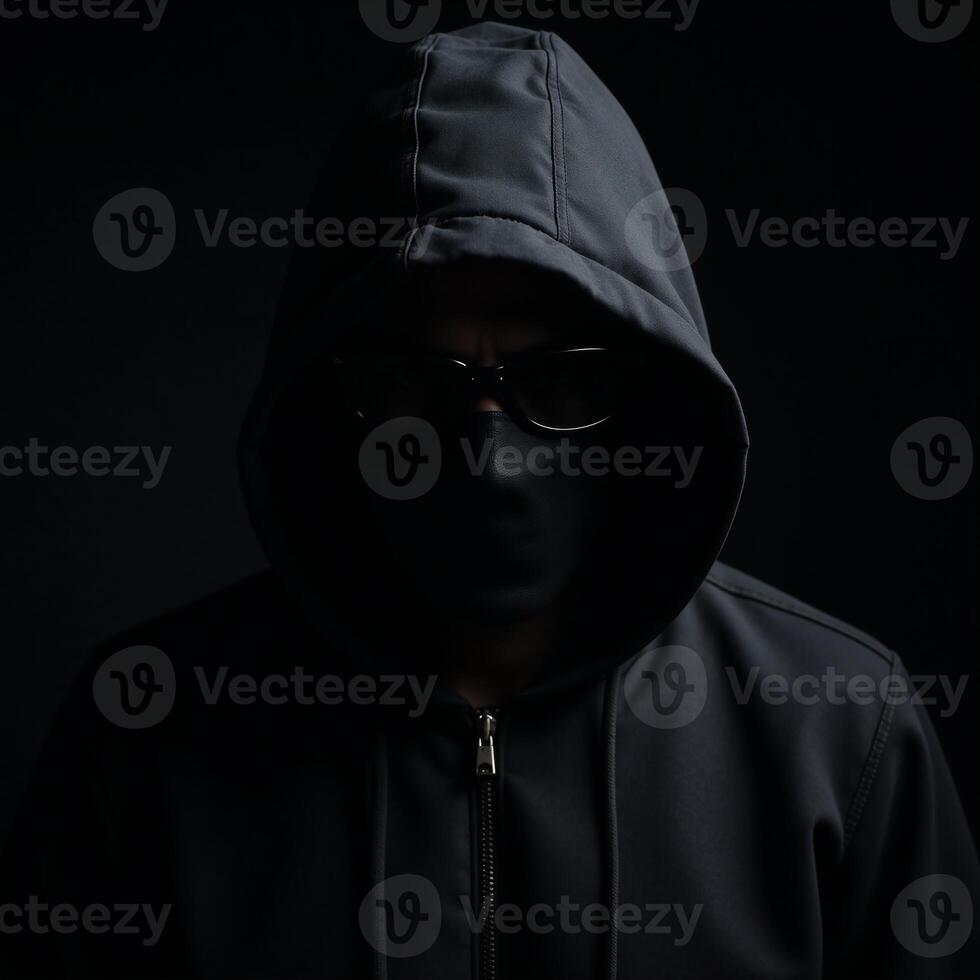 Dramatic portrait of a shadowyhooded bank robber on a dark backdrop photo