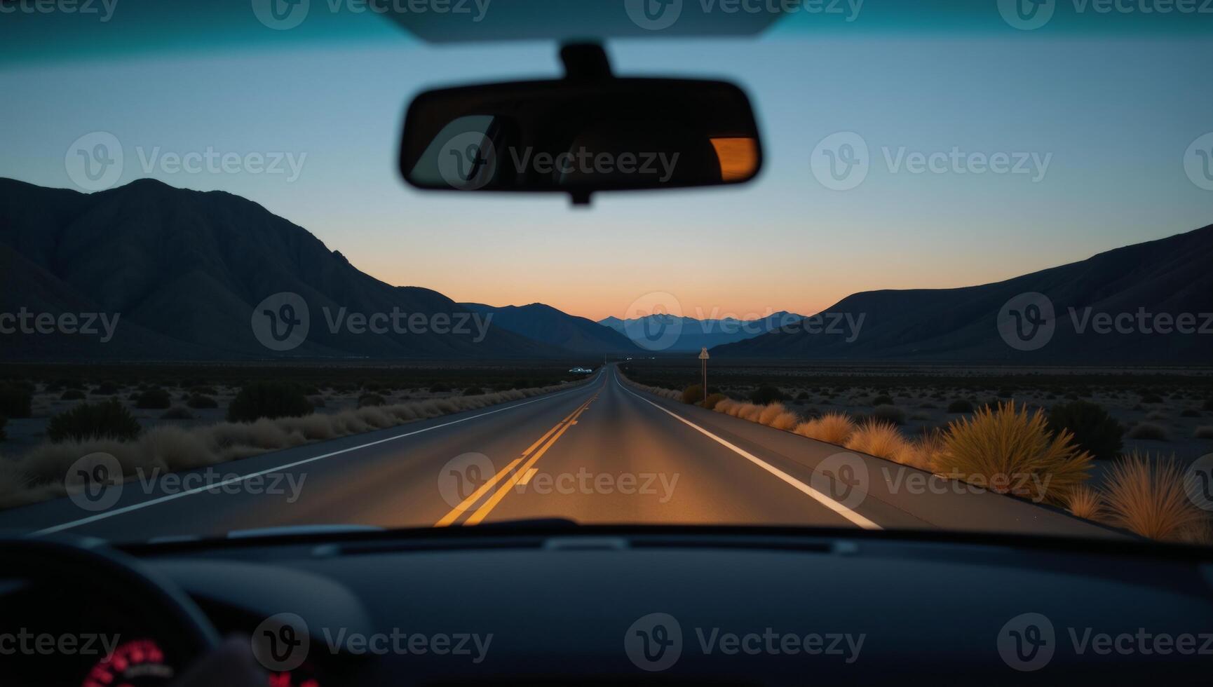 View from a cars rearview mirror featuring the road stretching out behind photo
