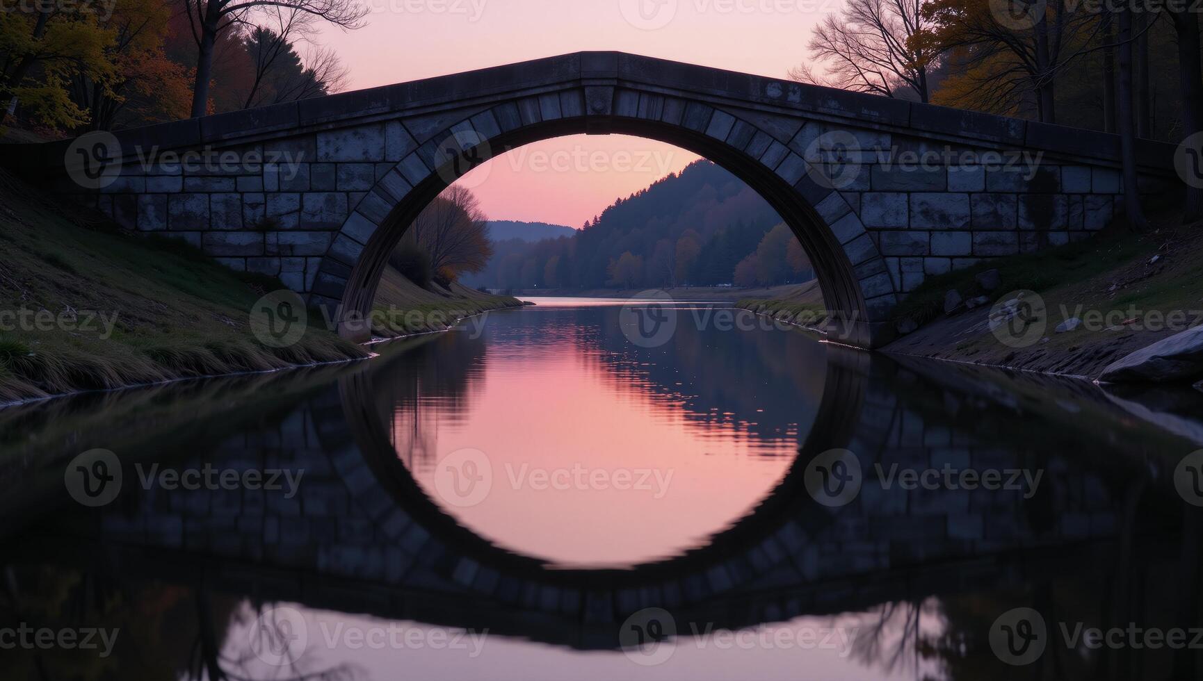 Stone bridge illuminated by soft pink light reflected on tranquil waters during twilight photo