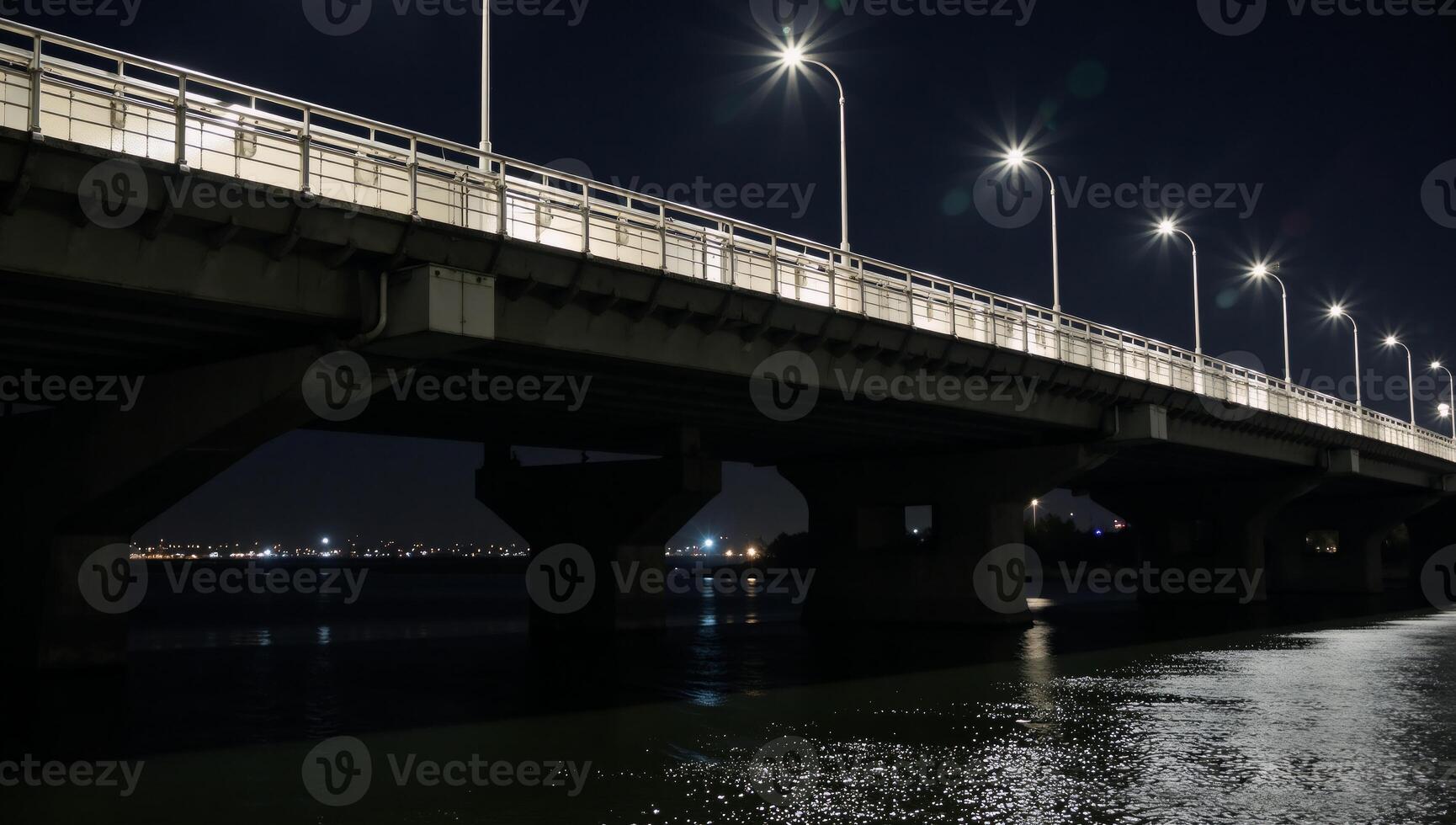 A litup city bridge showcases the glow from passing vehicles crossing during nighttime photo
