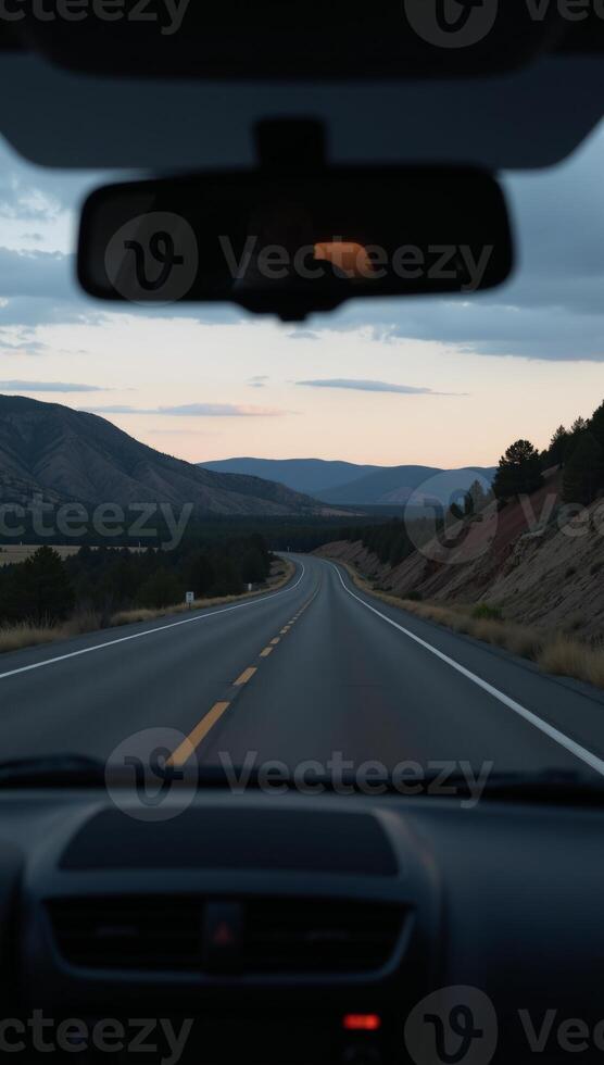 View from a cars rearview mirror featuring the road stretching out behind photo