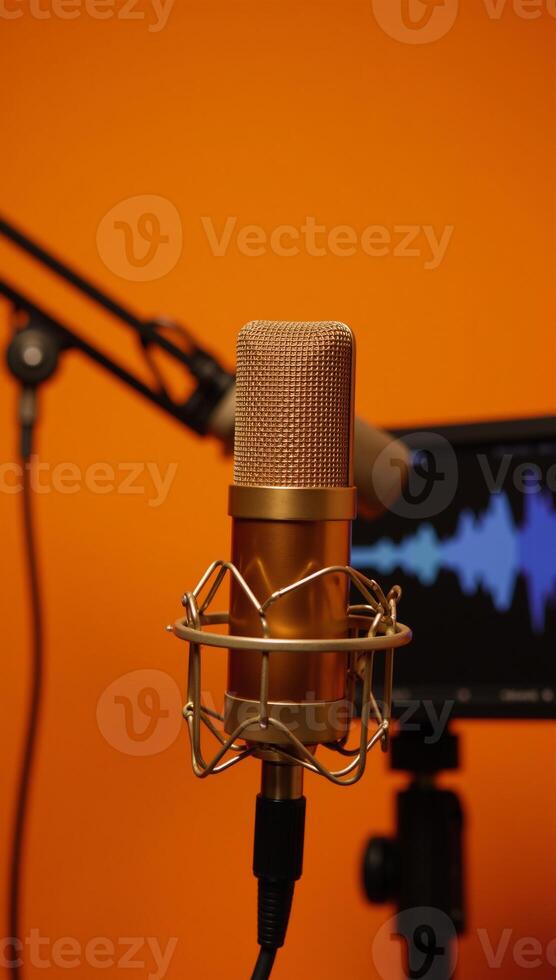 Golden mic and pop filter set up against sound waves on vivid orange backdrop professional recording setup photo