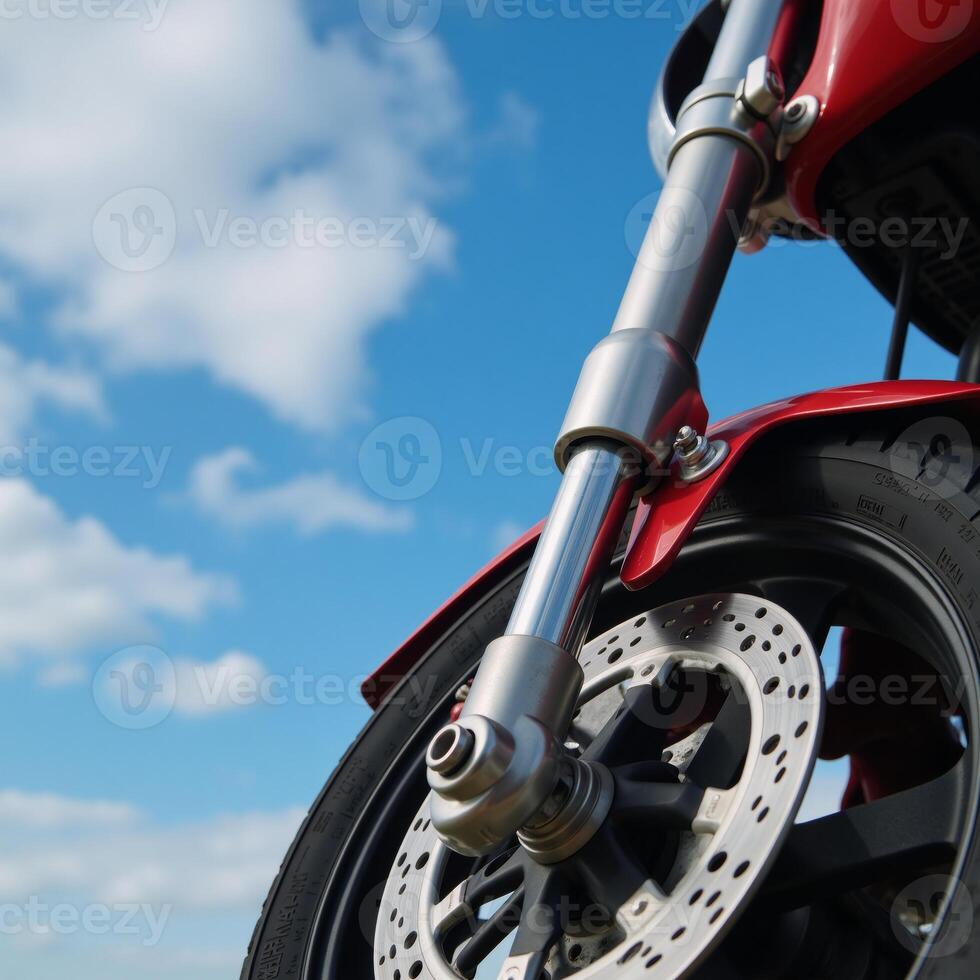 Detailed closeup image of shiny motorcycle wheel with intricate front suspension beneath a clear blue sky photo