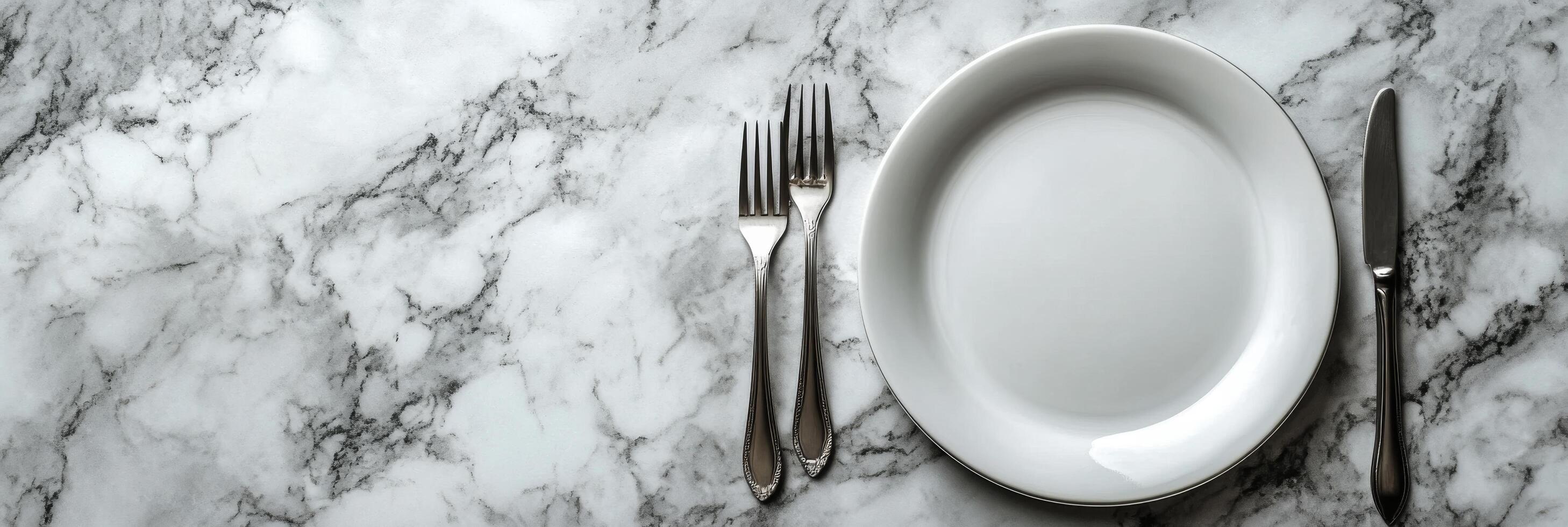 Elegant dining setup with a clean white plate and silver cutlery on a marble table photo