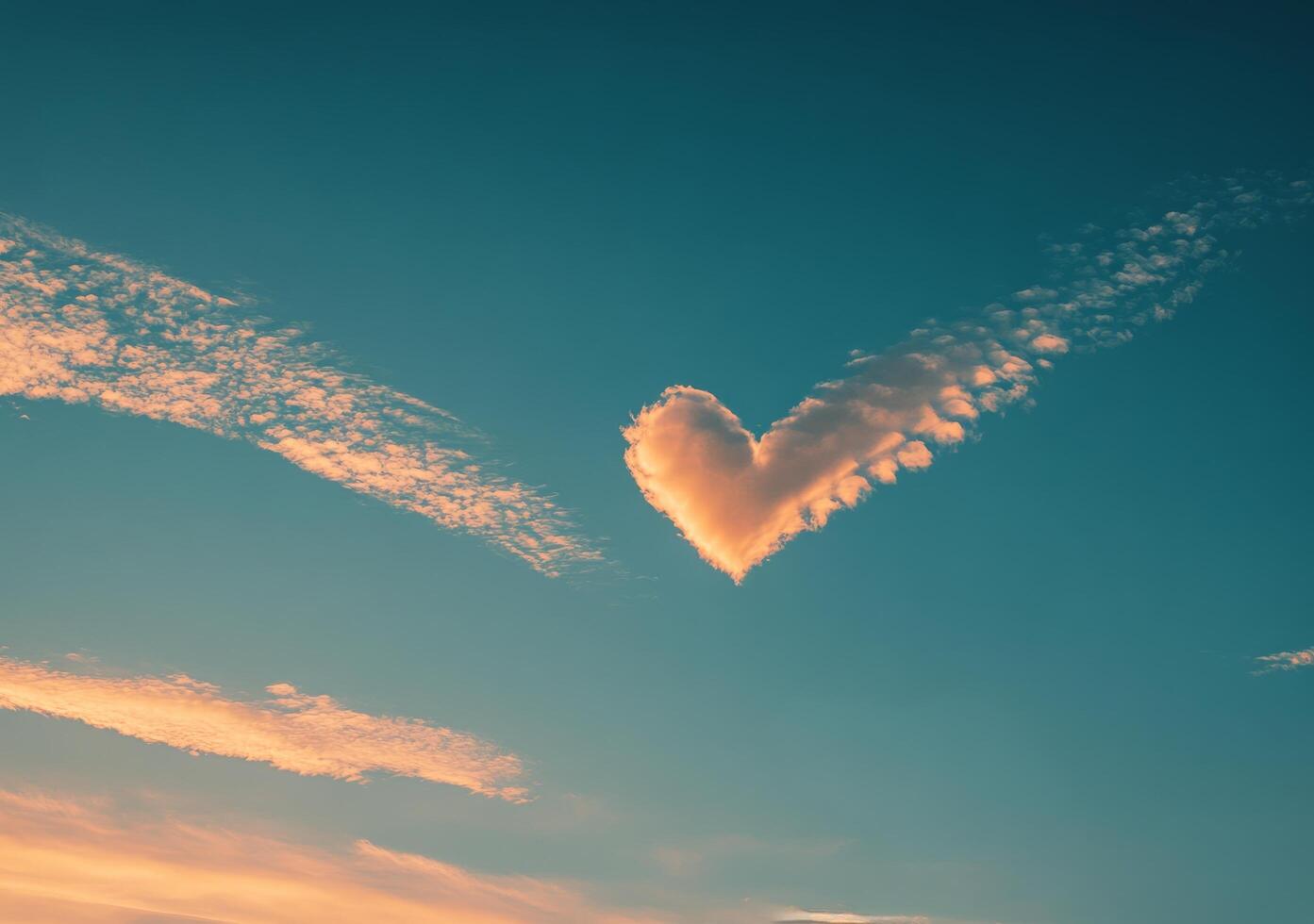 Heart shaped cloud floating in a clear blue sky during a sunny day with fluffy white clouds photo