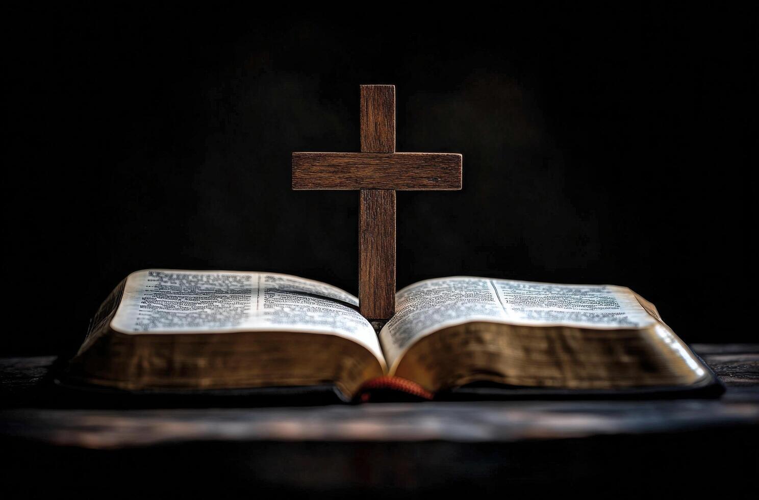 A wooden cross stands on an open Bible in a dimly lit room during evening hours photo