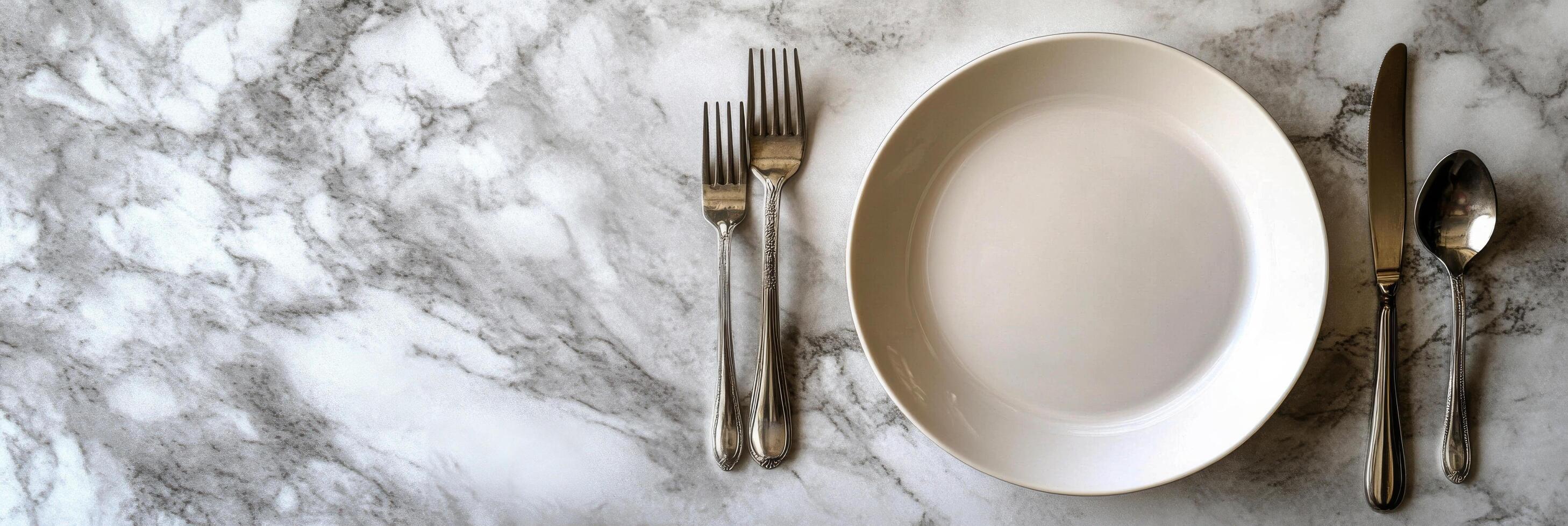 Elegant dining setup with a clean white plate and silver cutlery on a marble table photo
