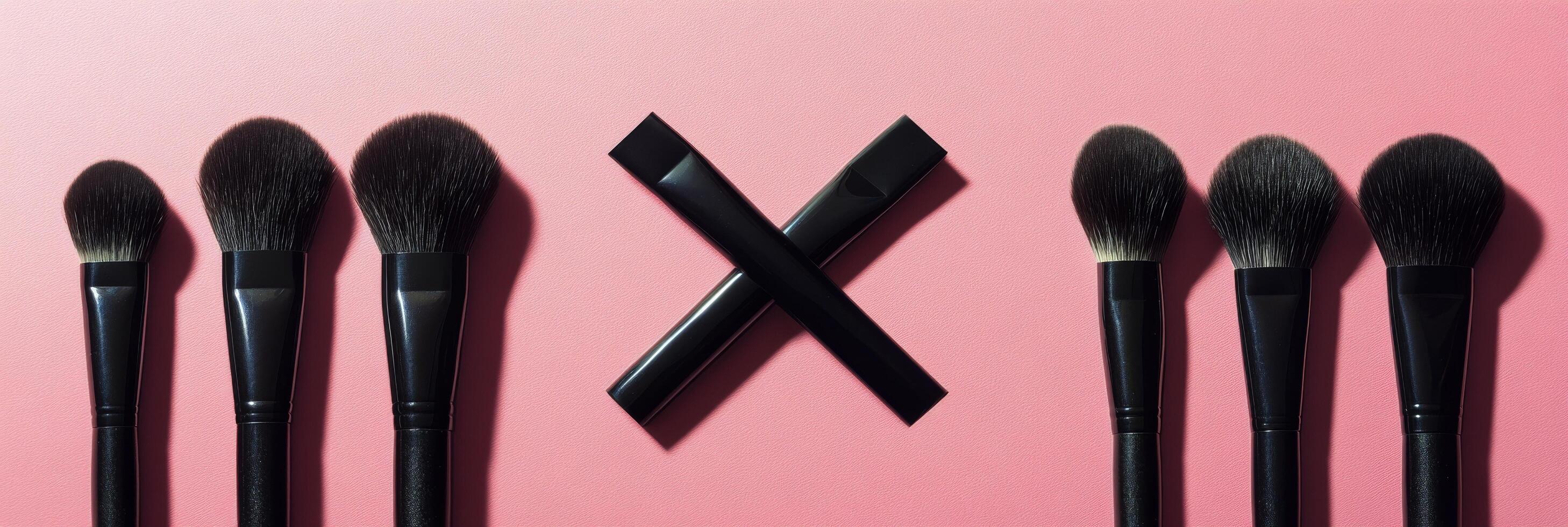 A set of makeup brushes in varying shapes on a pink background photo