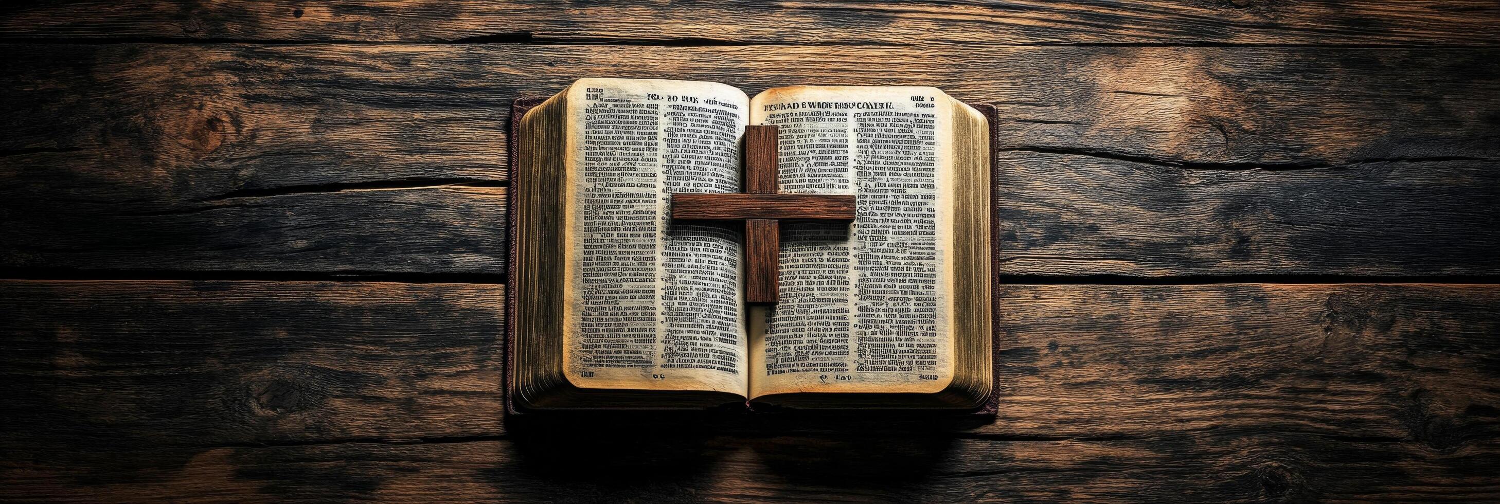 An open Bible resting on a wooden surface with a cross illuminated by soft light photo
