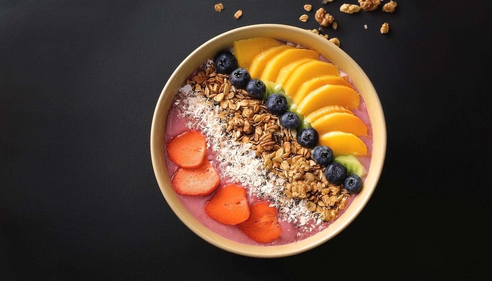 Smoothie bowl with fresh fruit and granola topping, on black background photo