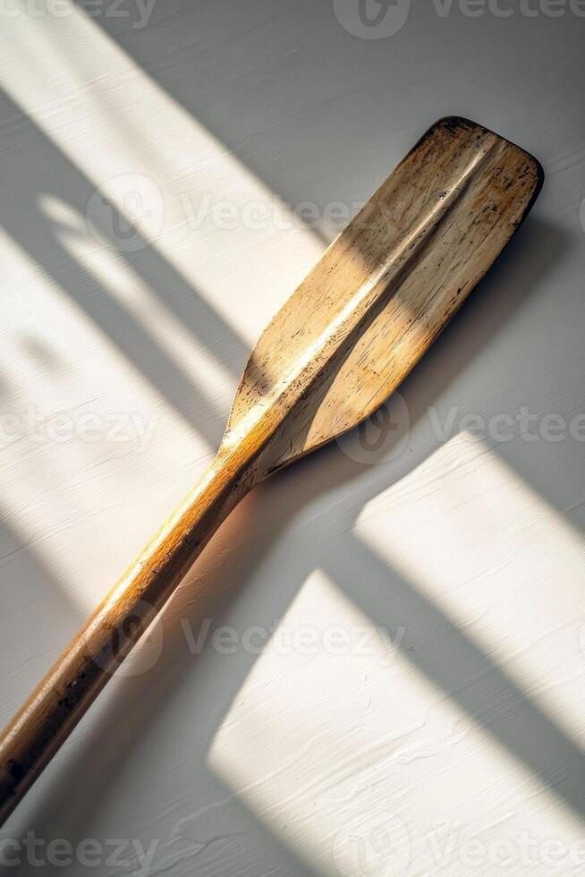 rowing oar is laid flat against a white background highlighting intricate details of the blade and handle. Soft shadows enhance the midday lighting creating a realistic aesthetic. photo