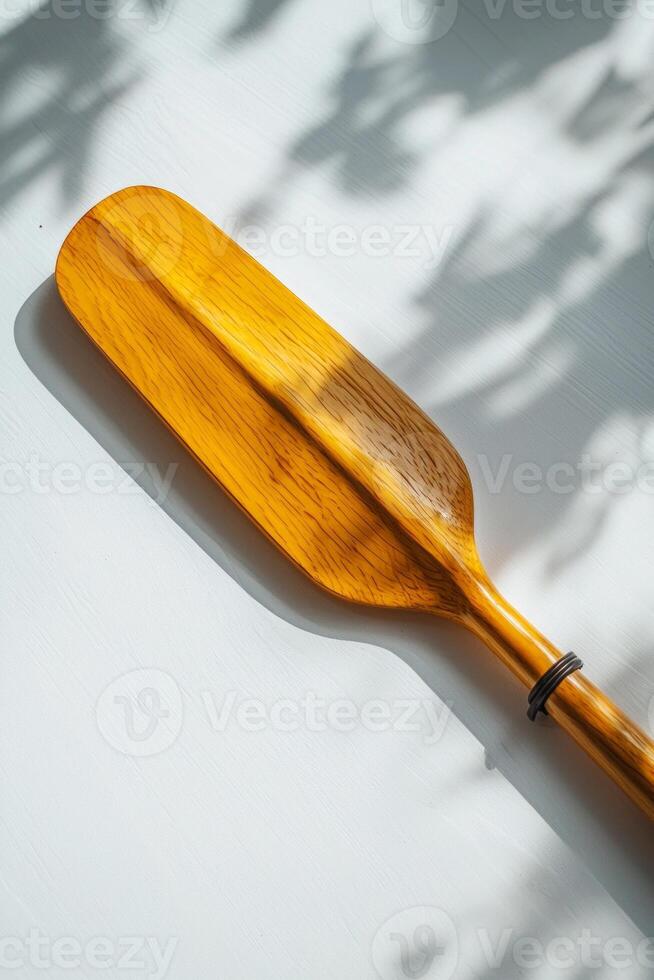 elegant design of a rowing oar resting flat against a white background. The soft midday light highlights the fine details of the blade and handle casting gentle shadows. photo