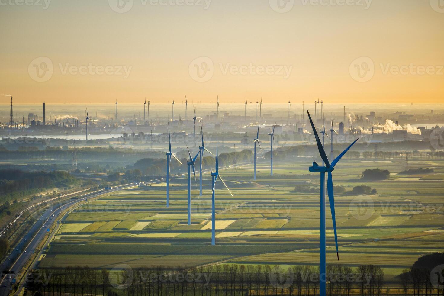 Aerial View on Waasland rural area mixed with wind turbines and harbor of Antwerp in the background during sunrise photo