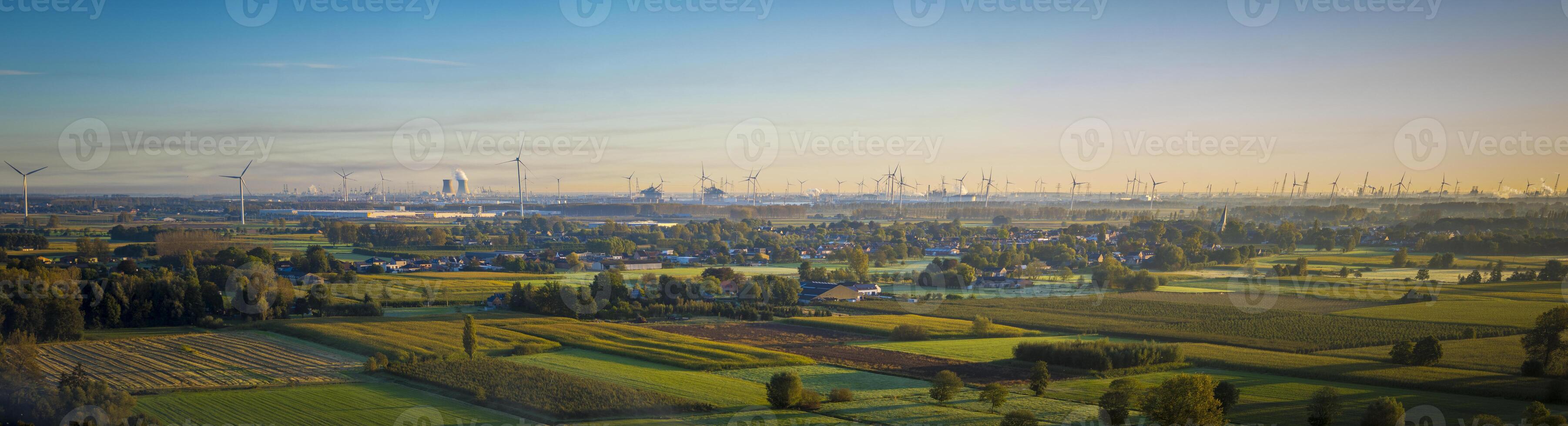 Aerial panorama view on Waasland rural area mixed with wind turbines and harbor of Antwerp in the far distance during sunrise photo