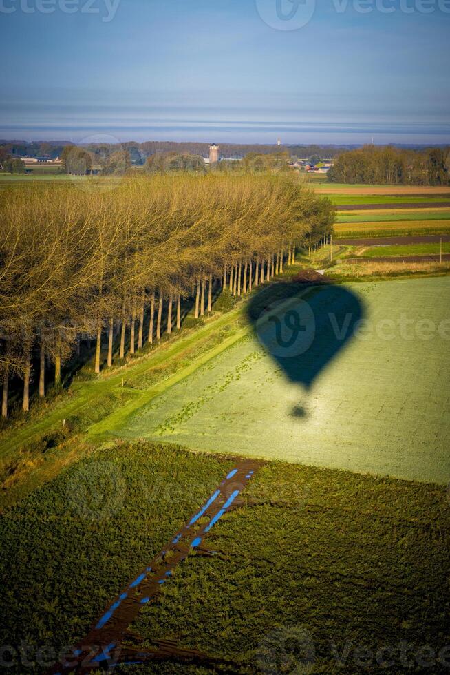 Vertical shot of hot air balloon casting a shadow over the fields photo