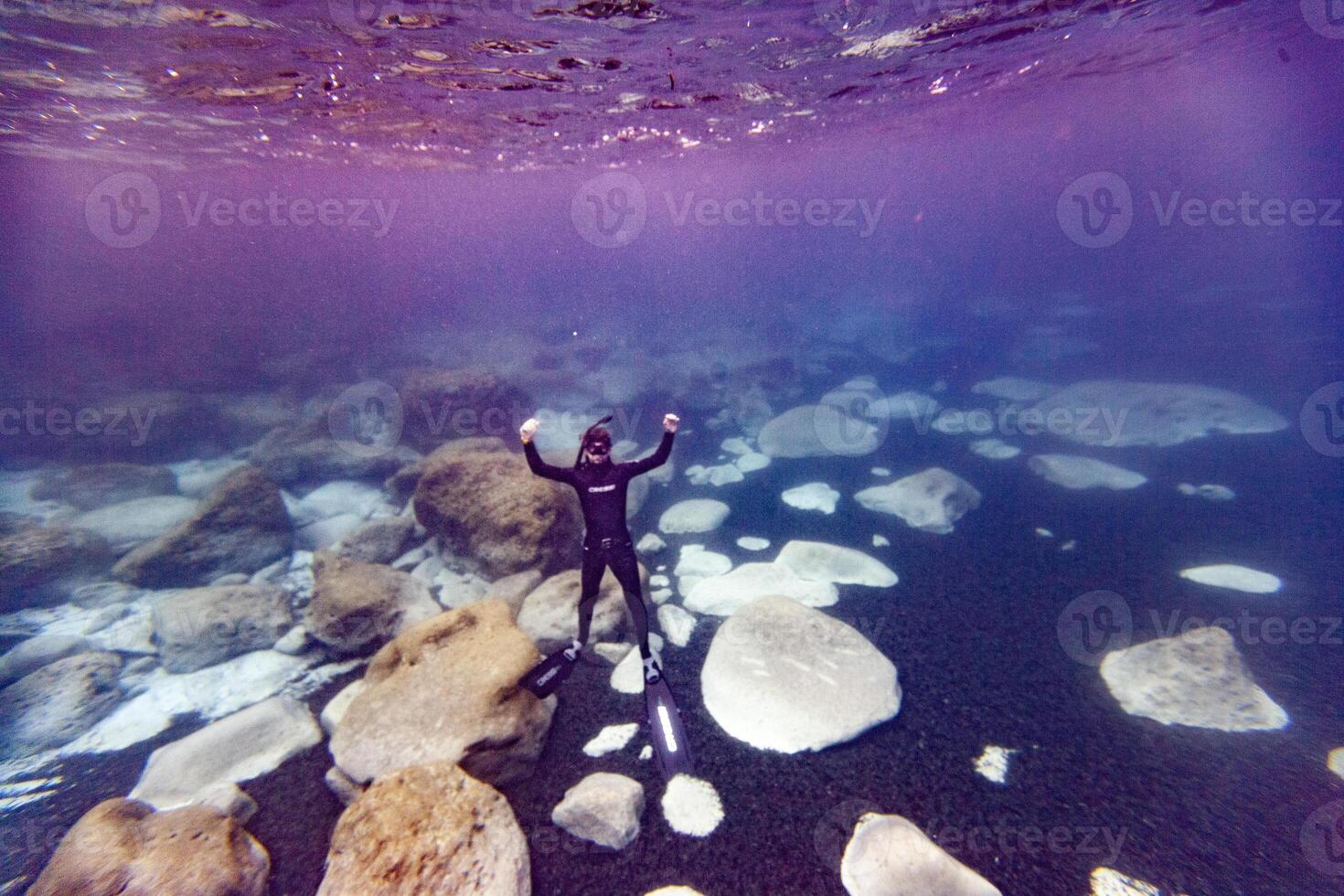 A person in a wetsuit standing on rocks photo