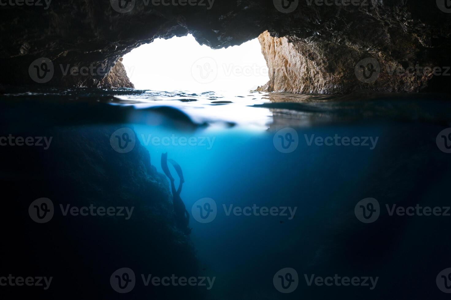 A cave with a light coming from the water photo