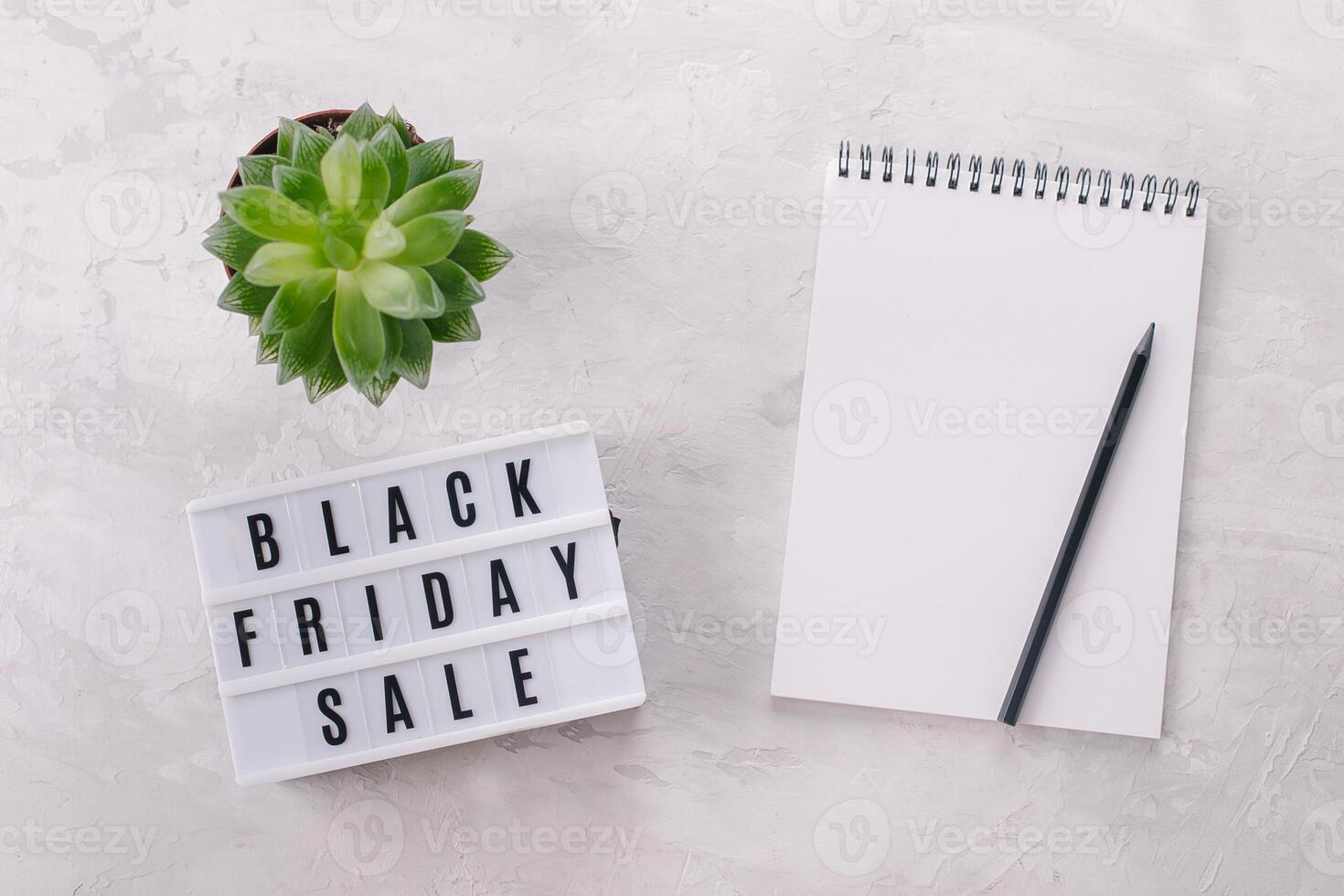 Black friday sale written on lightbox, plant, notebook with place for text, flat lay, copy space photo