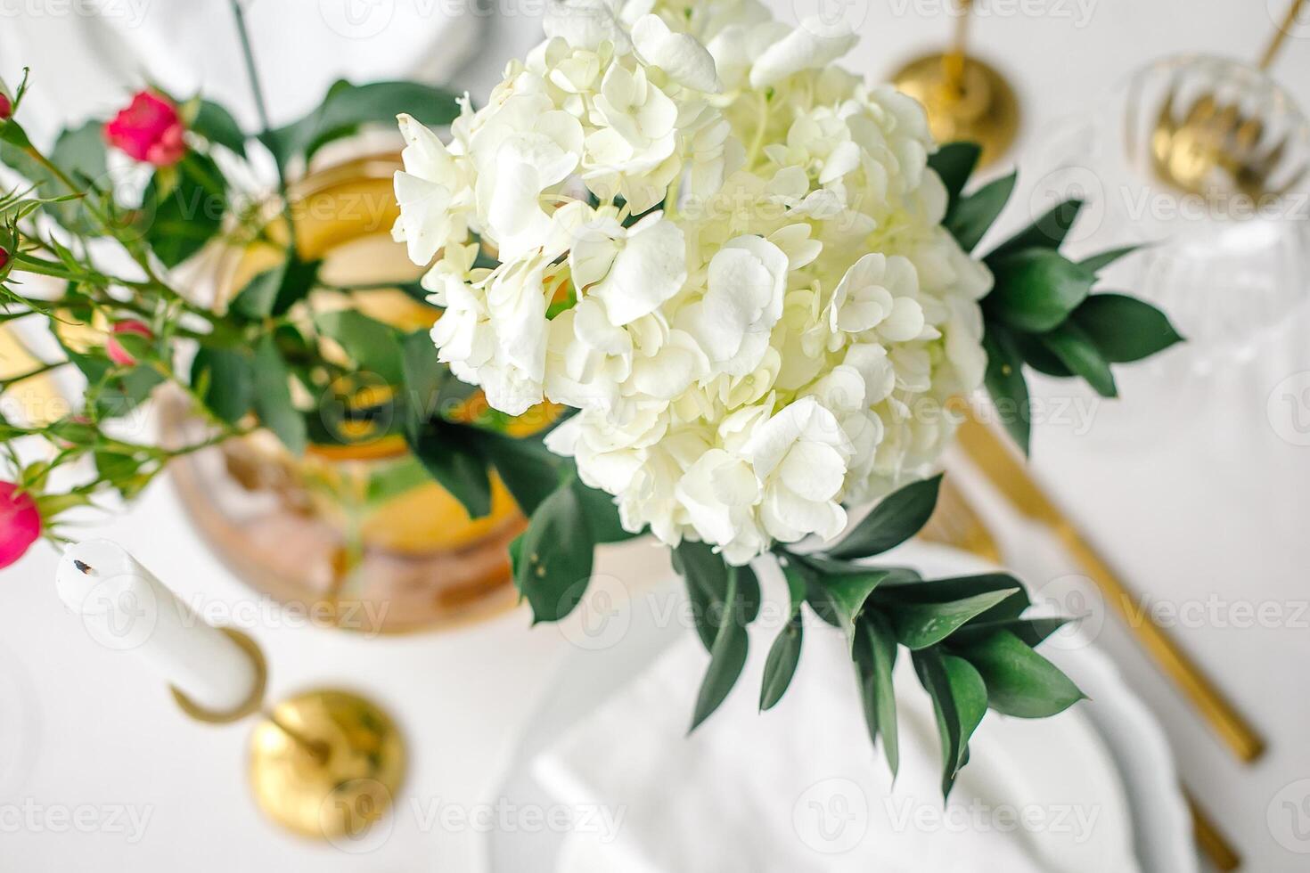 Top view of hydrangea flower, elegance classic table setting with white dishes, gold cutlery. photo