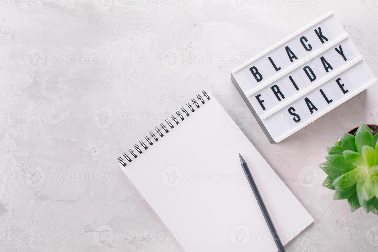 Black friday sale written on lightbox, plant, notebook with place for text, flat lay, copy space photo