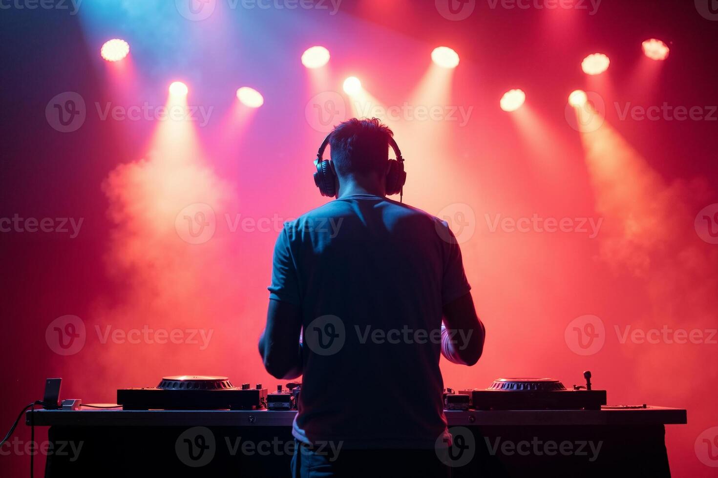 D.J. man standing in concert hall with smoke and colorful light enjoy music festival photo