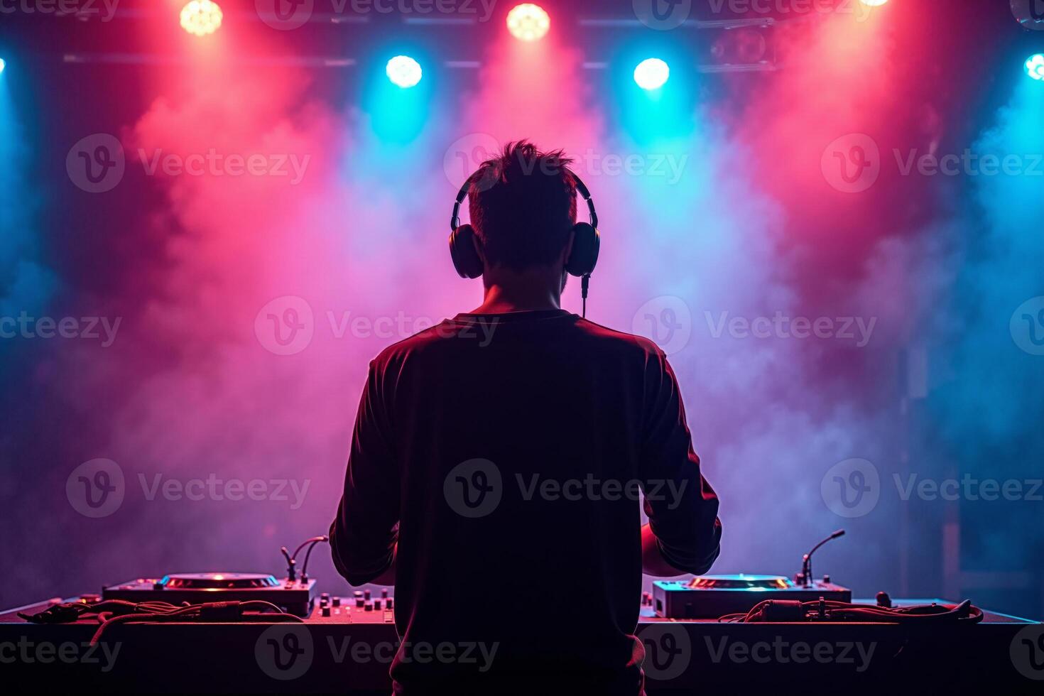 D.J. man standing in concert hall with smoke and colorful light enjoy music festival photo