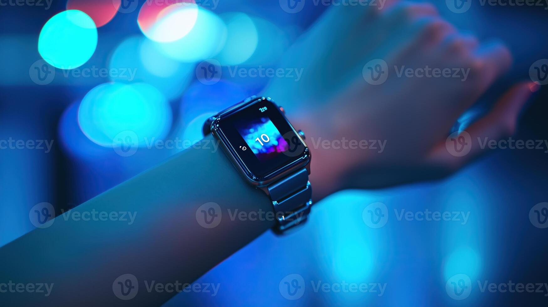 A hand wearing a smartwatch, resting gently against a blue background photo