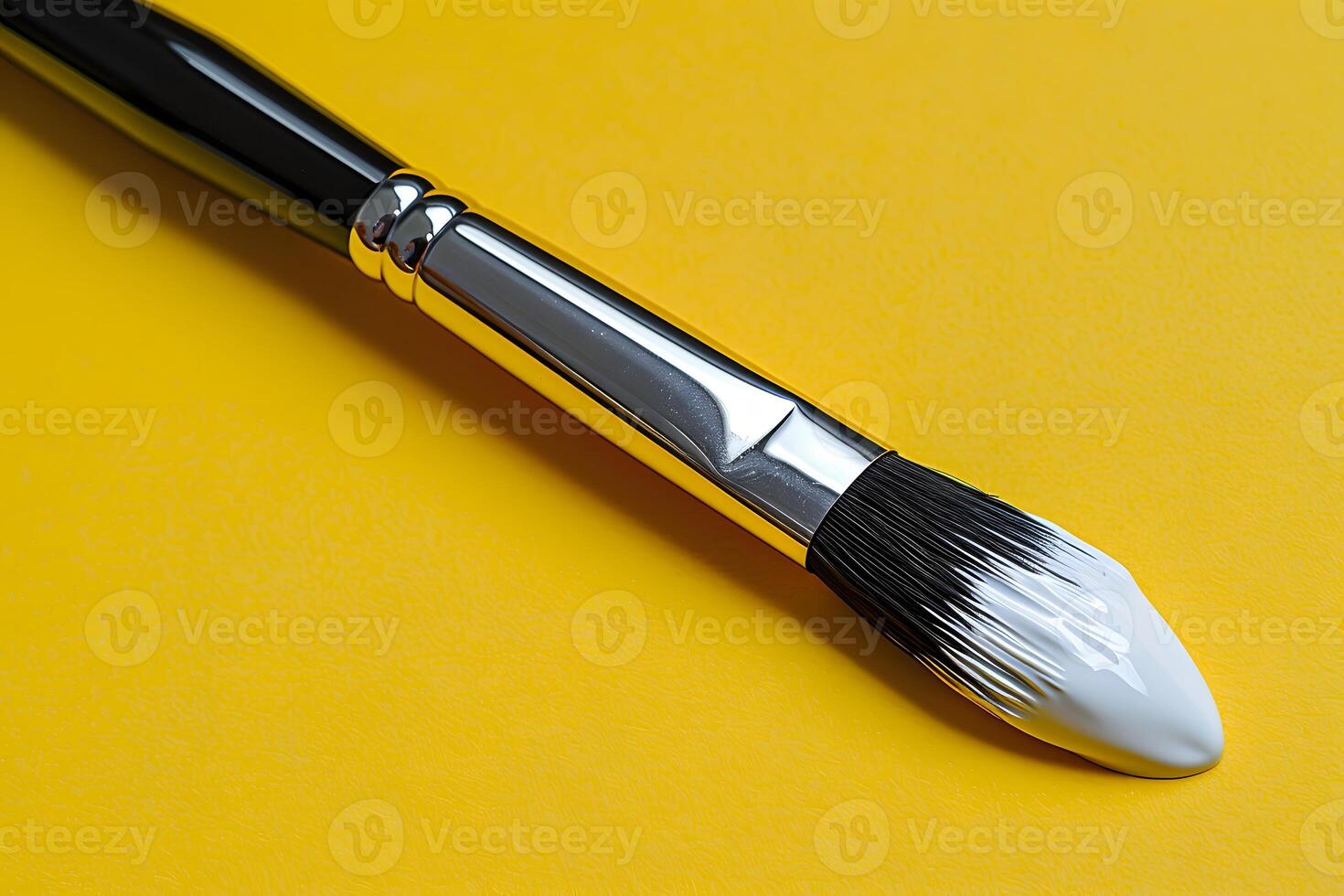 Artistic Paintbrush with White Paint on Bright Yellow Background for Creative Design Projects photo