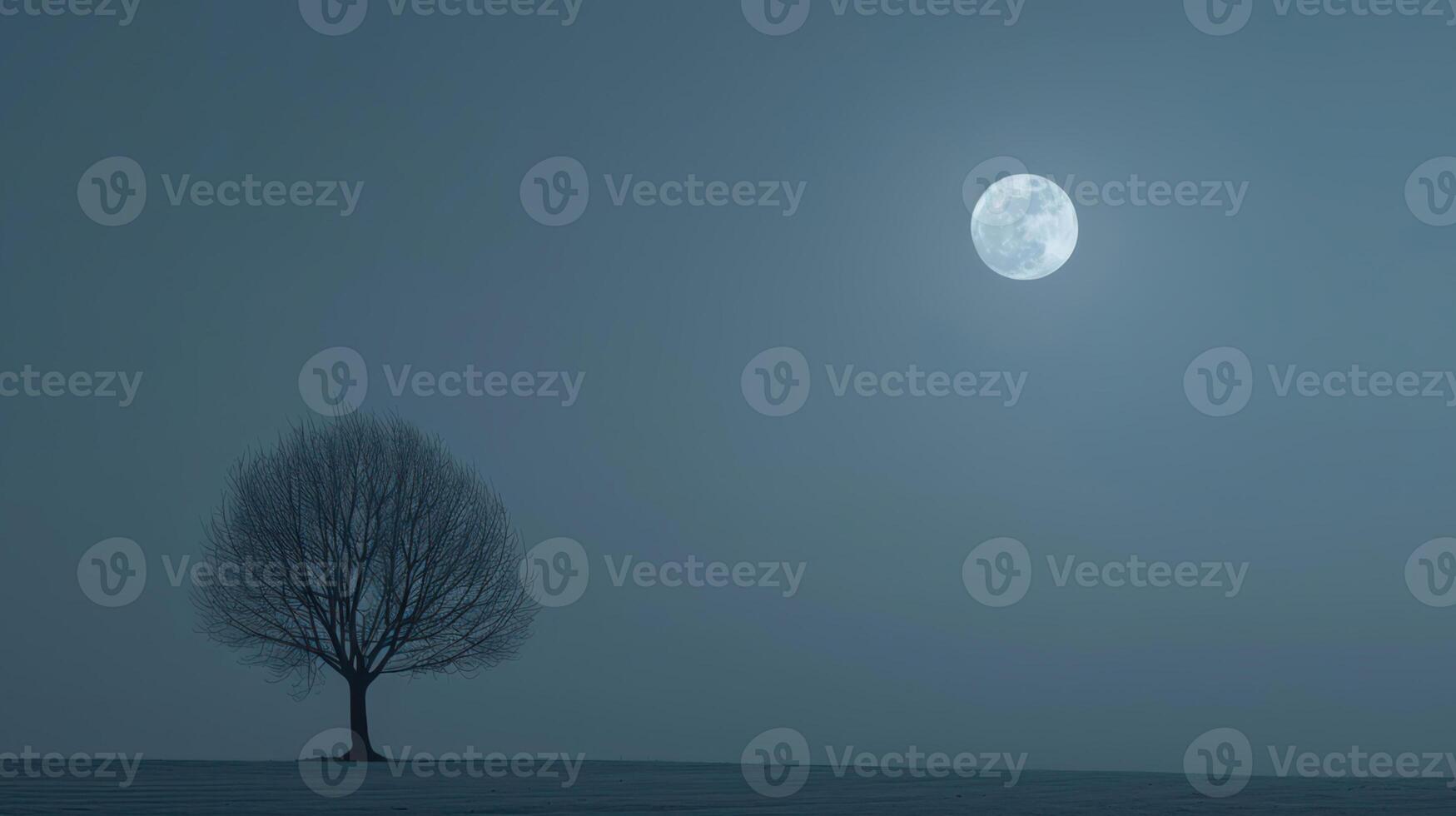 A lone tree stands in the middle of a snowy field photo