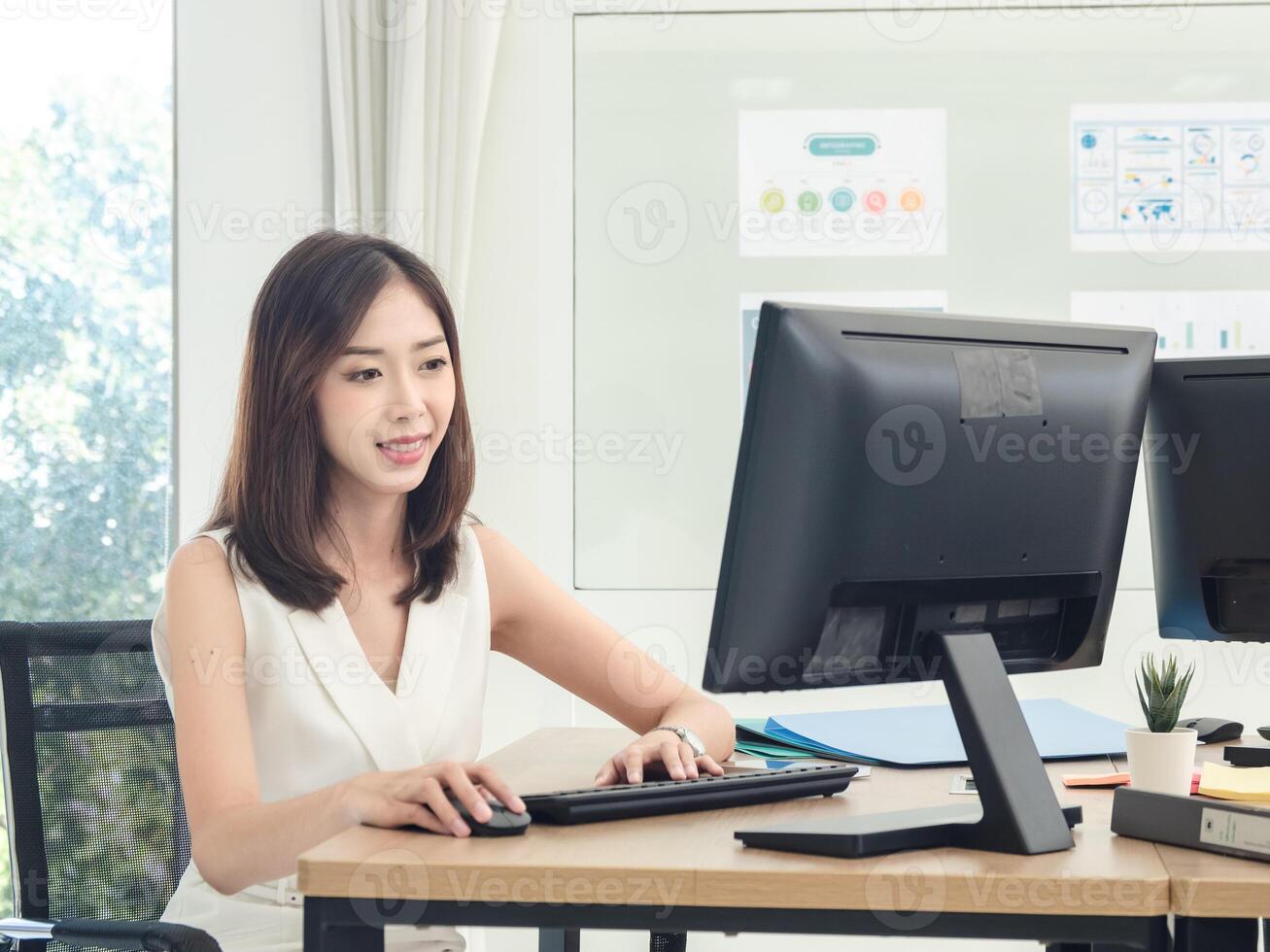 Manager employee woman girl asian one person smile happy enjoy sitting chair on desk looking hand holding notebook laptop ready for business working job online sale inside the room office company photo