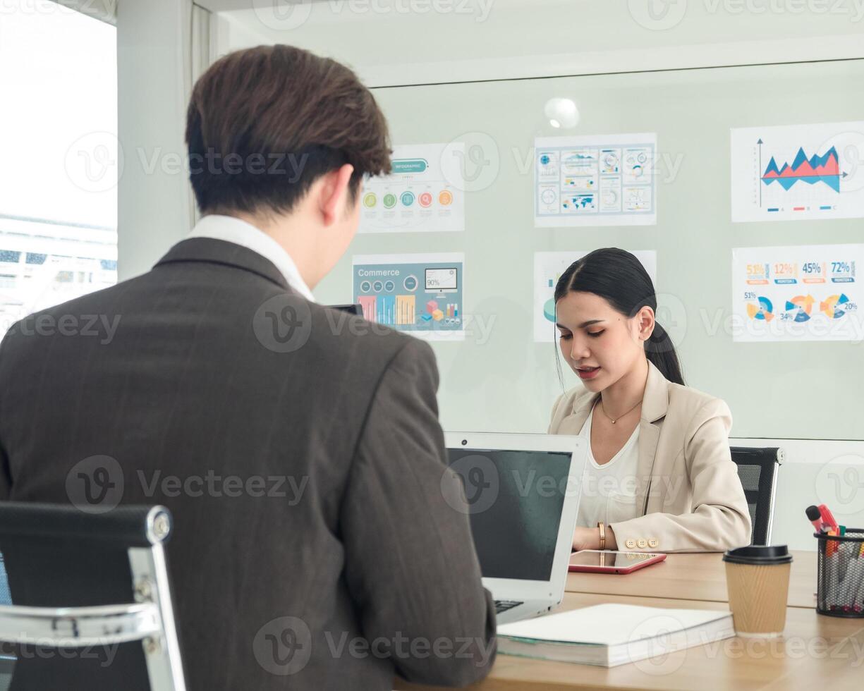 Business team woman and man asian group meeting sitting on desk looking talk think creative idea computer on table ready happy working new project job online product sale marketing in office company. photo