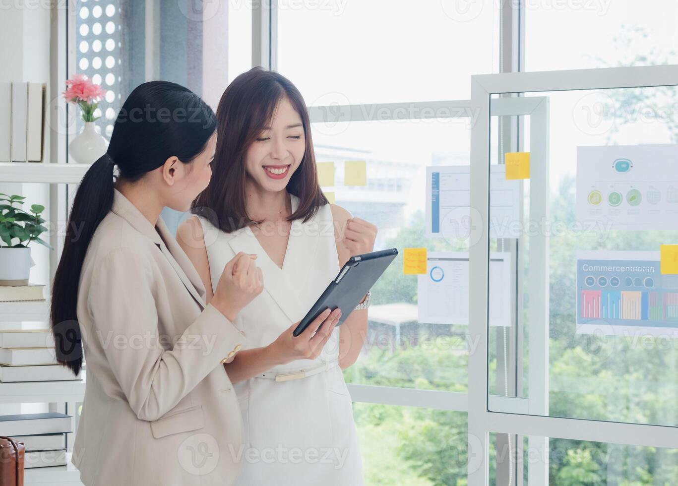 Business portrait two person woman asian standing smile cheerful talk looking holding tablet and hands up happy with in agreement ready new project job for work in room office company white background photo