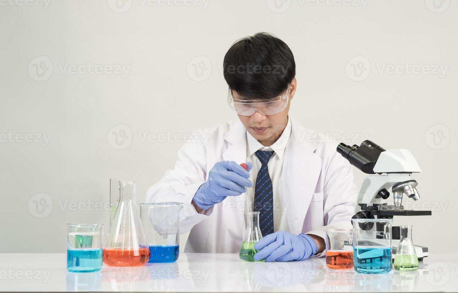 Man asian student education learning scientist wearing doctor gown in lab looking hand at chemist. caused by mixing reagents in scientific research laboratories with test tubes and microscope on table photo
