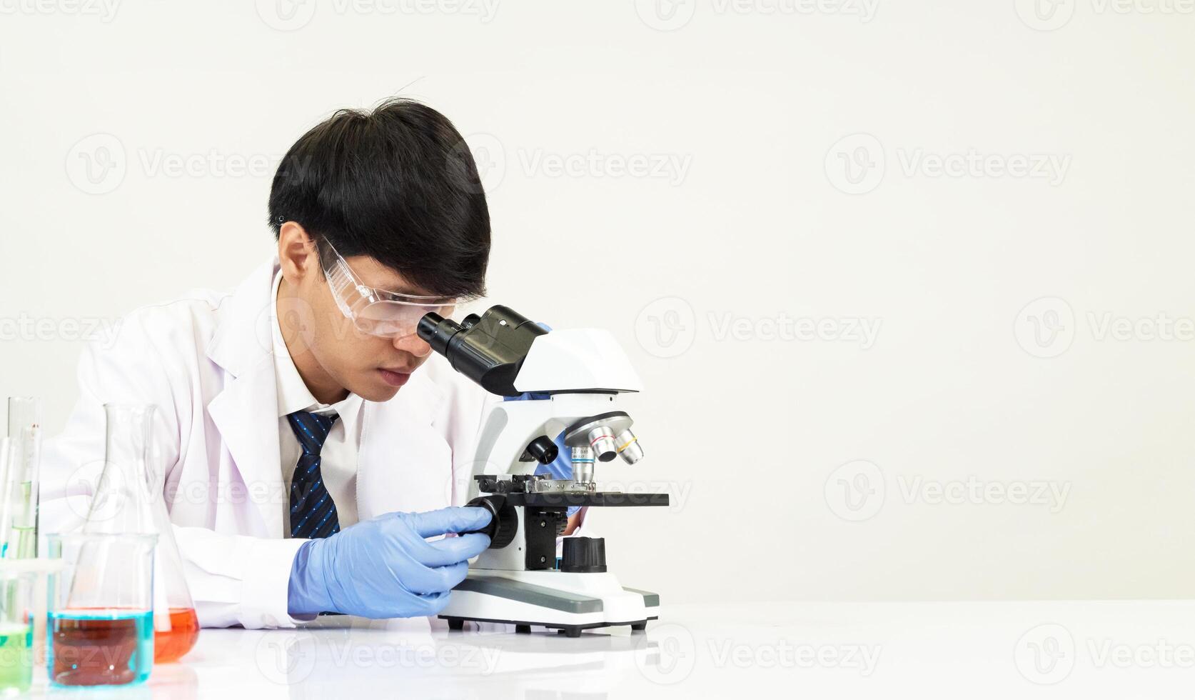 Man asian student education learning scientist wearing doctor gown in lab looking hand at chemist. caused by mixing reagents in scientific research laboratories with test tubes and microscope on table photo