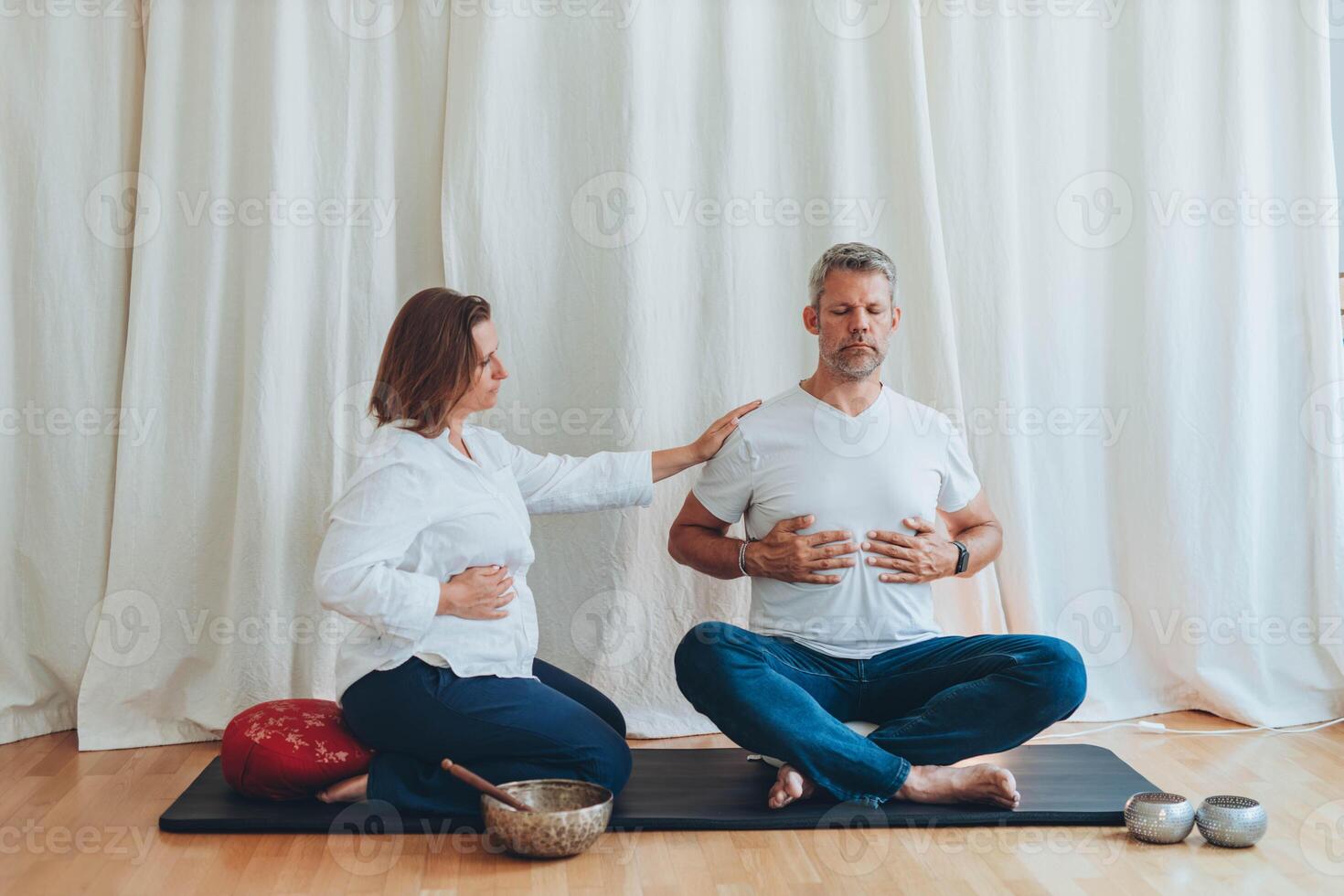 Man and woman practicing mindful breathing together during a meditation session,seated on mats with sound bowls photo