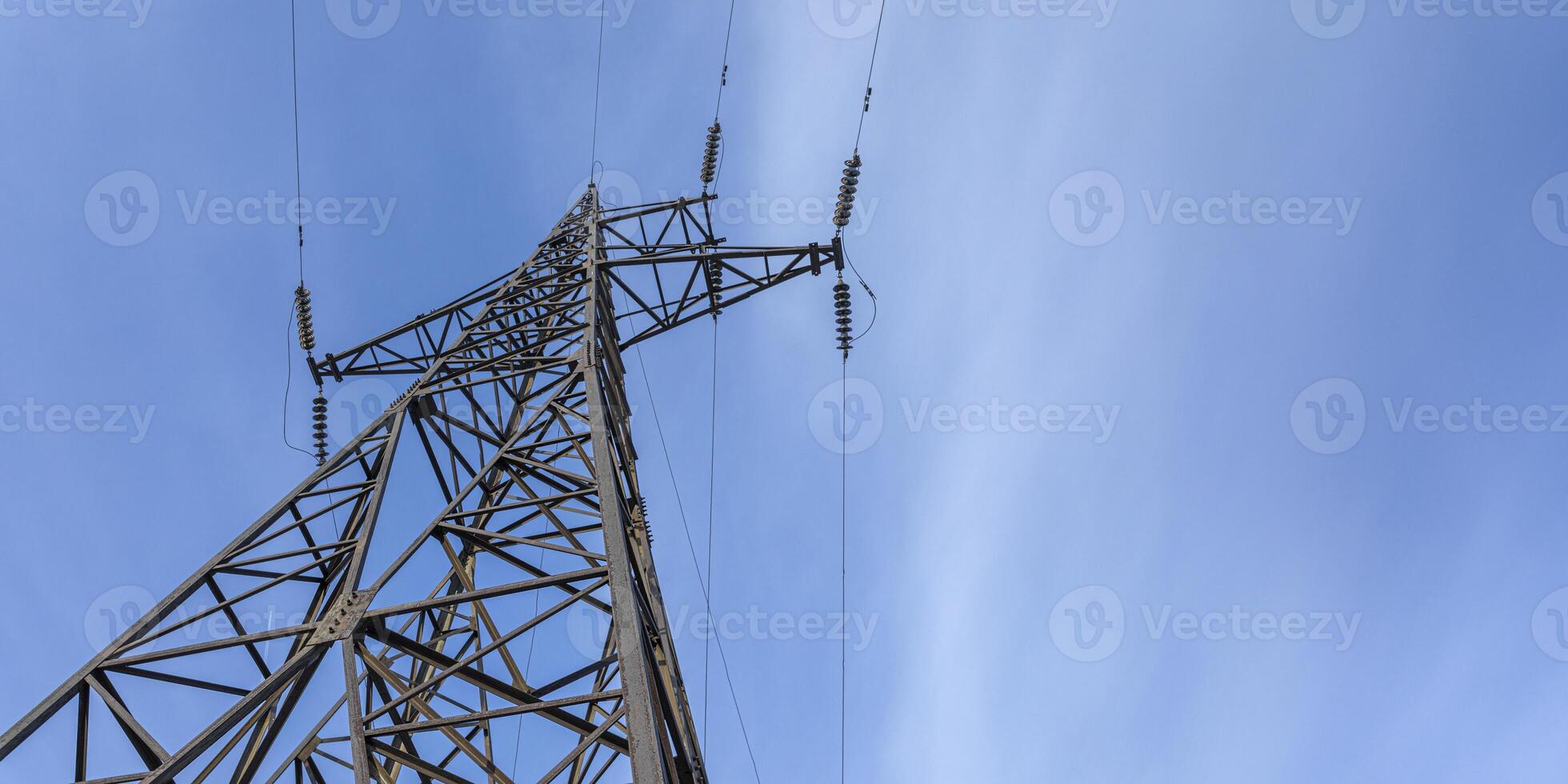 Tower of high voltage transmission stands tall against blue sky with clouds. Banner. Copy space. photo