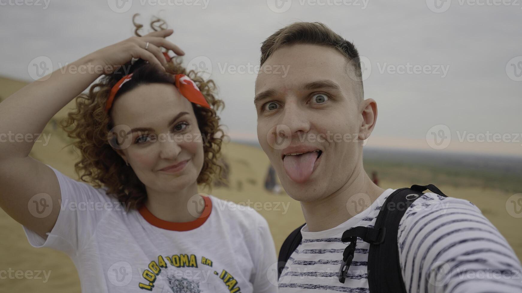 Couple traveling takes selfie picture on sand dunes at sunset. Action. Young couple taking selfies, people travel concept. photo